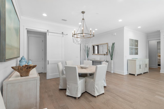 dining room featuring light wood-type flooring, a barn door, and crown molding