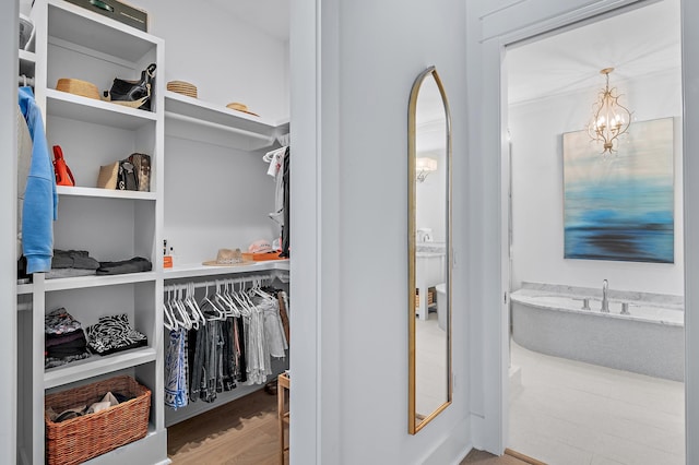 walk in closet featuring light hardwood / wood-style flooring and a notable chandelier