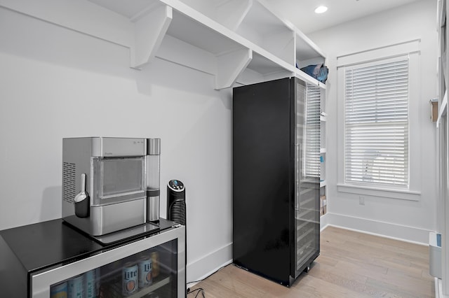 kitchen with black fridge, light hardwood / wood-style floors, and wine cooler