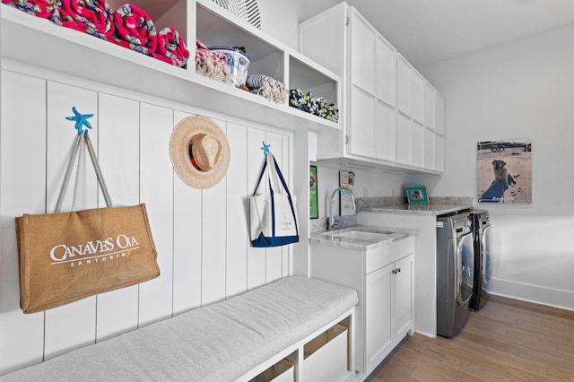 laundry area featuring cabinets, hardwood / wood-style floors, washer and clothes dryer, and sink