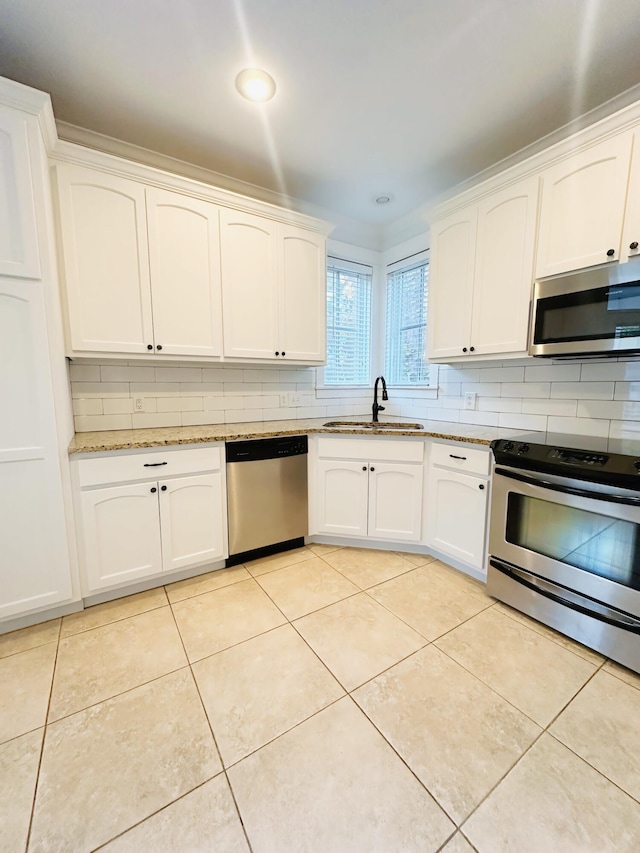 kitchen featuring sink, stainless steel appliances, light tile patterned floors, decorative backsplash, and white cabinets