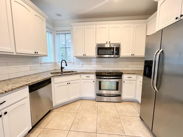 kitchen featuring sink, light stone counters, backsplash, white cabinets, and appliances with stainless steel finishes