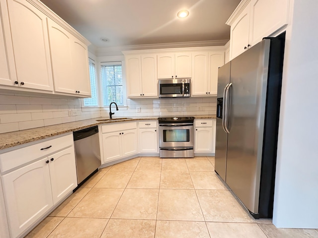 kitchen with light stone counters, stainless steel appliances, crown molding, sink, and light tile patterned floors