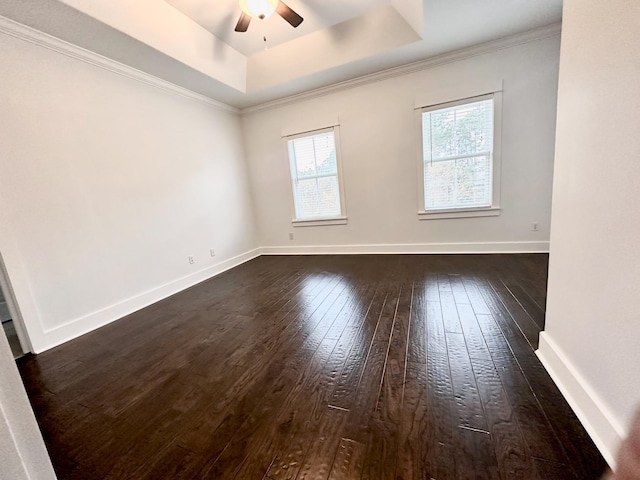 empty room featuring ceiling fan, ornamental molding, dark wood-type flooring, and a tray ceiling