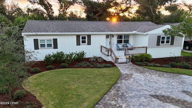 ranch-style house featuring a porch and a lawn