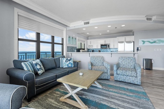 living room featuring a water view, crown molding, and a healthy amount of sunlight