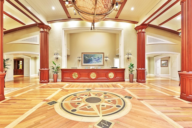 interior space with decorative columns, hardwood / wood-style floors, a towering ceiling, and basketball court