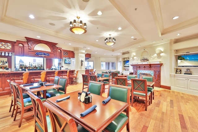 dining room featuring a notable chandelier, a raised ceiling, crown molding, and light hardwood / wood-style flooring