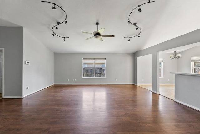 unfurnished living room with ceiling fan with notable chandelier, dark hardwood / wood-style flooring, rail lighting, and a wealth of natural light