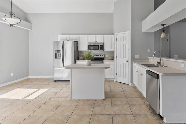 kitchen with a high ceiling, white cabinets, sink, appliances with stainless steel finishes, and decorative light fixtures