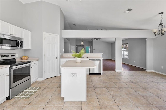 kitchen featuring stainless steel appliances, a kitchen island, pendant lighting, vaulted ceiling, and white cabinets