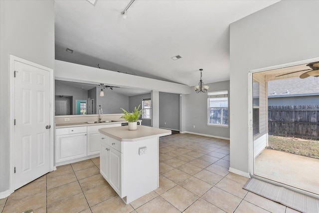 kitchen featuring ceiling fan with notable chandelier, vaulted ceiling, a kitchen island, sink, and white cabinetry