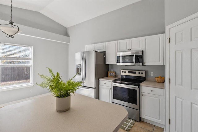 kitchen with hanging light fixtures, white cabinets, lofted ceiling, light tile patterned floors, and appliances with stainless steel finishes