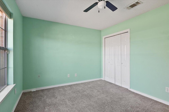 unfurnished bedroom featuring ceiling fan, a closet, carpet, and a textured ceiling