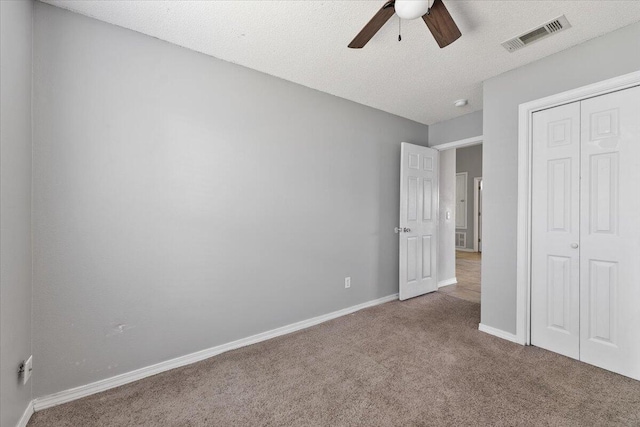 unfurnished bedroom featuring carpet flooring, ceiling fan, a closet, and a textured ceiling