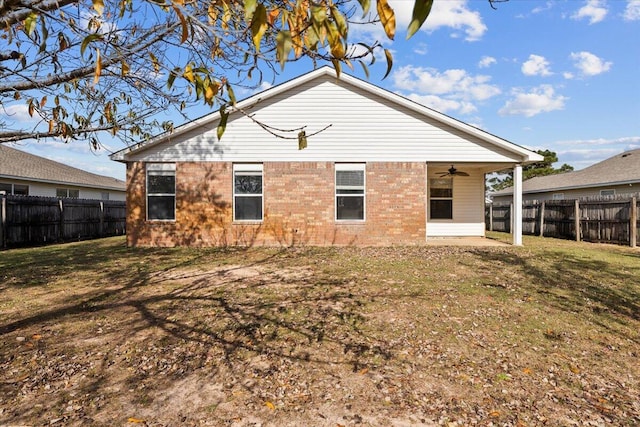 back of property featuring ceiling fan and a yard