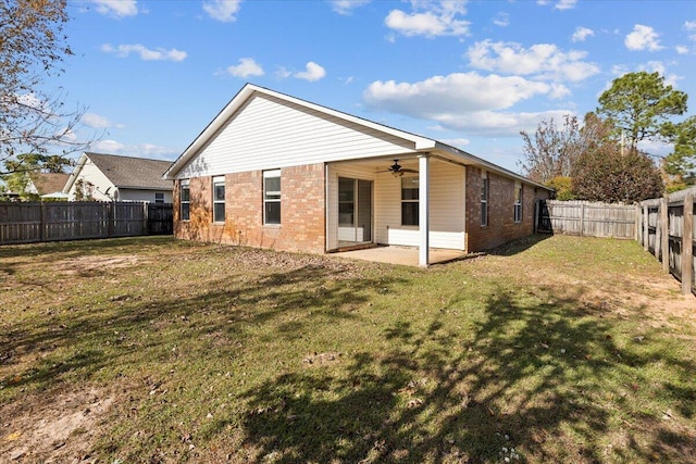 rear view of house with ceiling fan, a patio area, and a yard