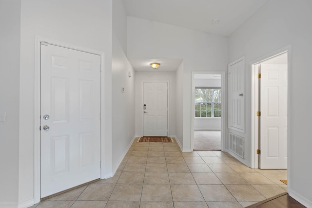 foyer entrance featuring lofted ceiling, light tile patterned floors, baseboards, and visible vents