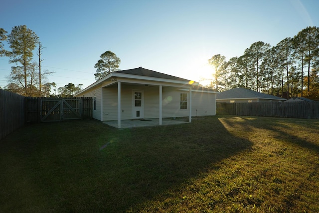 back of house with a patio and a lawn