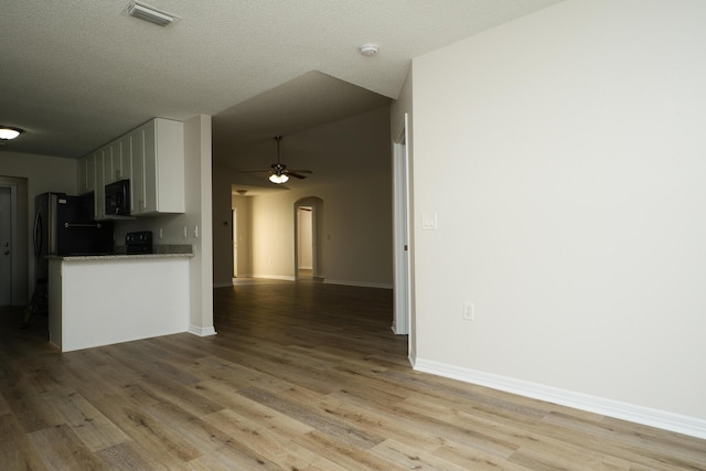 kitchen featuring white cabinets, light wood-type flooring, a textured ceiling, and refrigerator