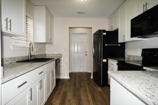 kitchen featuring light stone countertops, white cabinetry, sink, and black appliances