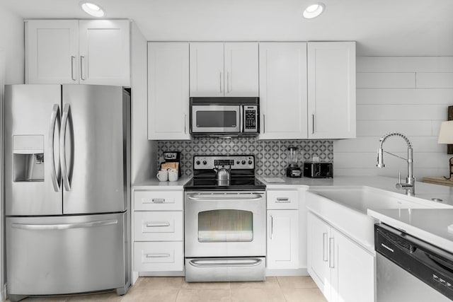 kitchen featuring sink, white cabinets, light tile patterned flooring, and appliances with stainless steel finishes