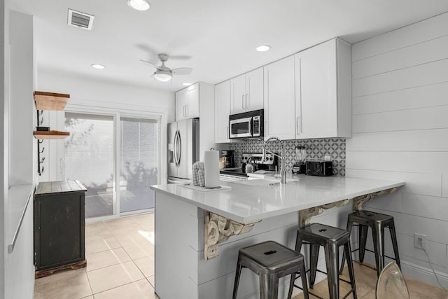 kitchen with white cabinets, a breakfast bar, kitchen peninsula, and stainless steel appliances