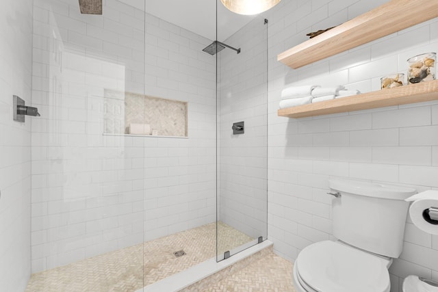 bathroom with toilet, tile walls, and a tile shower