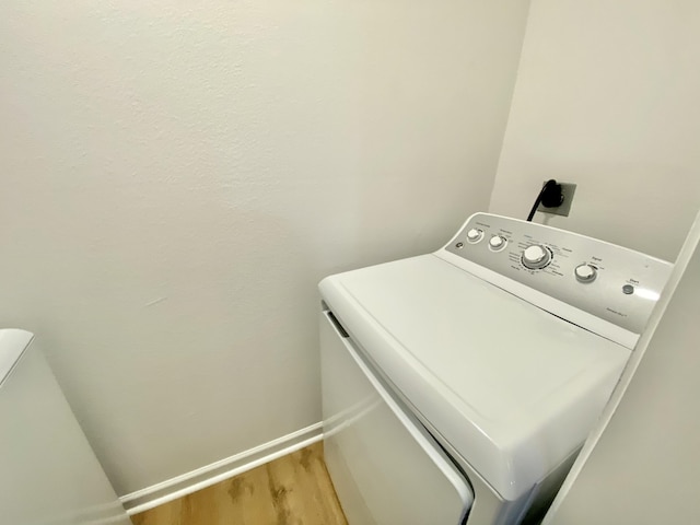 clothes washing area featuring hardwood / wood-style flooring and washer / dryer