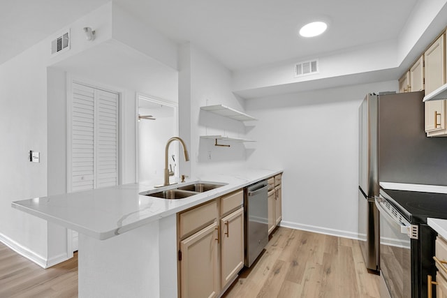 kitchen with kitchen peninsula, stainless steel appliances, ceiling fan, sink, and light hardwood / wood-style flooring