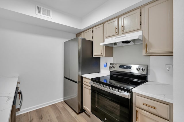 kitchen with light stone countertops, appliances with stainless steel finishes, and light hardwood / wood-style flooring