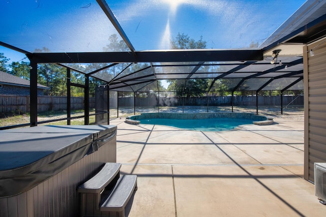 view of pool with glass enclosure, a patio, and a hot tub