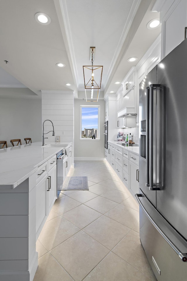 kitchen featuring white cabinets, crown molding, light tile patterned floors, decorative light fixtures, and stainless steel appliances