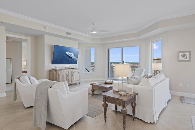 living room featuring ceiling fan, a raised ceiling, ornamental molding, and light tile patterned floors