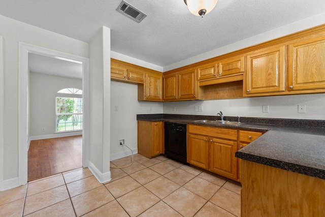kitchen with sink, light tile patterned floors, a textured ceiling, and black dishwasher