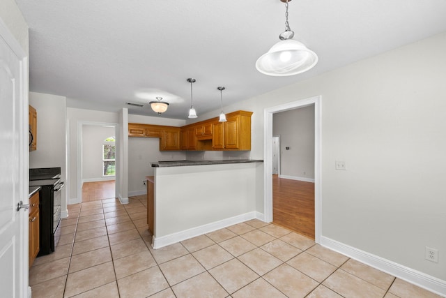 kitchen with kitchen peninsula, light tile patterned floors, electric range, and decorative light fixtures