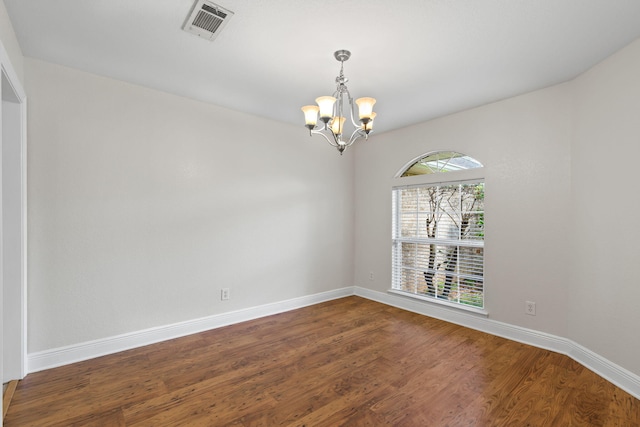 spare room featuring hardwood / wood-style flooring and a notable chandelier