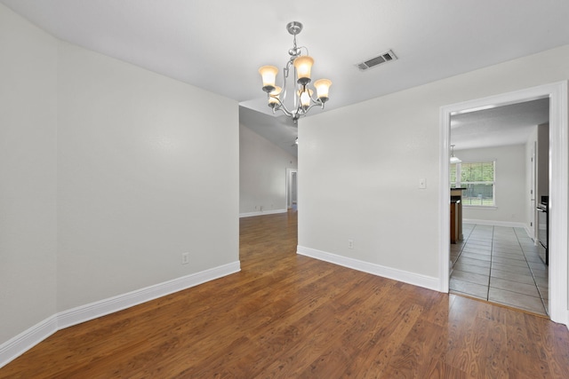 unfurnished room featuring a chandelier and wood-type flooring