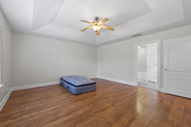 interior space featuring ceiling fan, dark wood-type flooring, and a tray ceiling