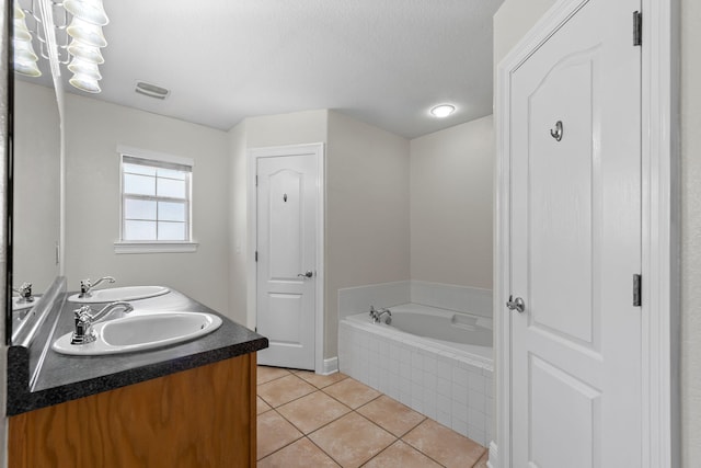 bathroom featuring tile patterned floors, vanity, a textured ceiling, and tiled bath