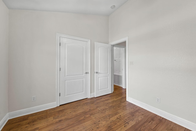 unfurnished bedroom with dark wood-type flooring and high vaulted ceiling