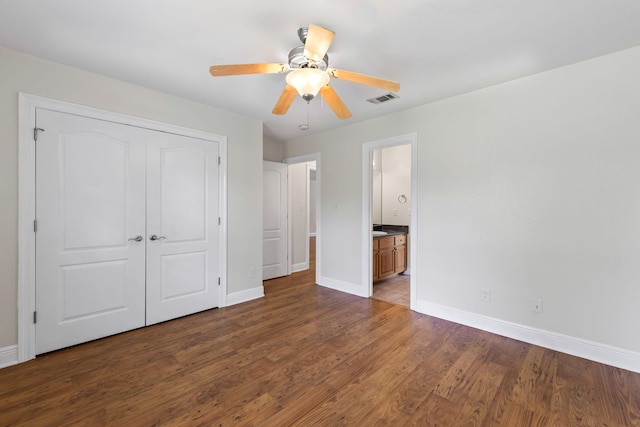 unfurnished bedroom featuring a closet, dark hardwood / wood-style flooring, ceiling fan, and ensuite bathroom