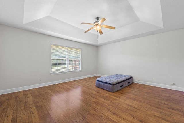 interior space featuring a tray ceiling, ceiling fan, and dark wood-type flooring