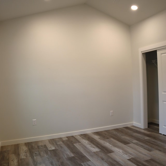 unfurnished room featuring vaulted ceiling and dark wood-type flooring