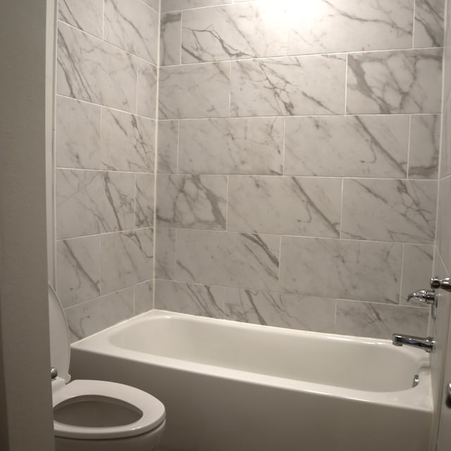 bathroom with tiled shower / bath combo and toilet