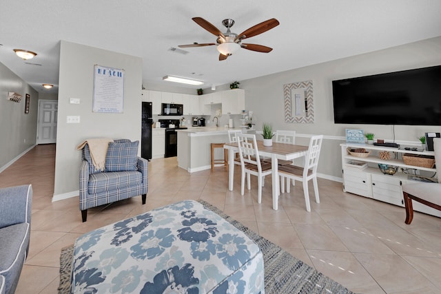 living room with ceiling fan, sink, light tile patterned floors, and a textured ceiling