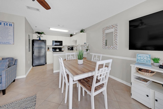 tiled dining space with ceiling fan, sink, and a textured ceiling