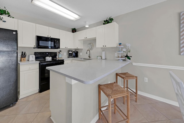 kitchen with kitchen peninsula, a breakfast bar, white cabinets, and black appliances