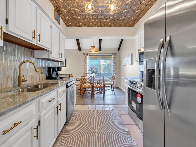 kitchen featuring white cabinets, lofted ceiling with beams, sink, appliances with stainless steel finishes, and decorative light fixtures