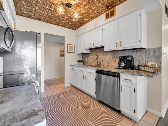 kitchen with sink, decorative backsplash, appliances with stainless steel finishes, light tile patterned flooring, and white cabinetry